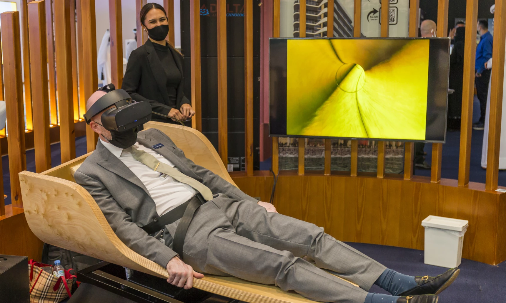 a man at an event sat on a moving segment of a waterslide simulator wearing a VR headset