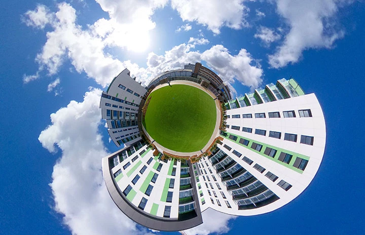 A garden surrounded by tall buildings warped to appear like a planet floating in the sky
