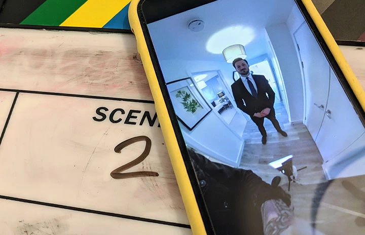a phone screen with a picture of a man in a suit standing in a hallway