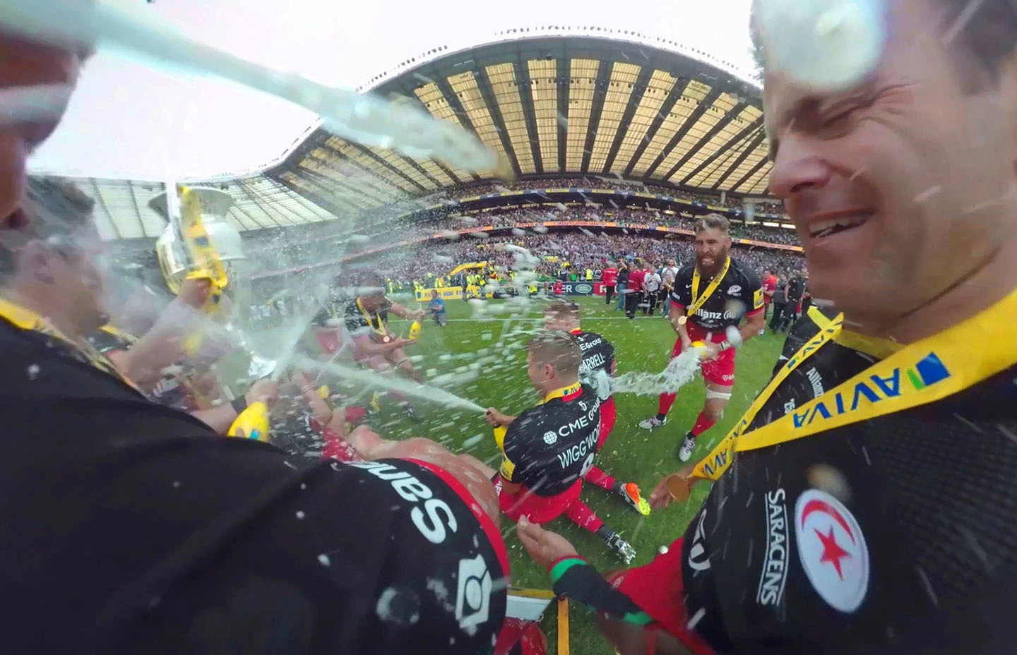 Rugby players celebrating on pitch with fizzing champagne
