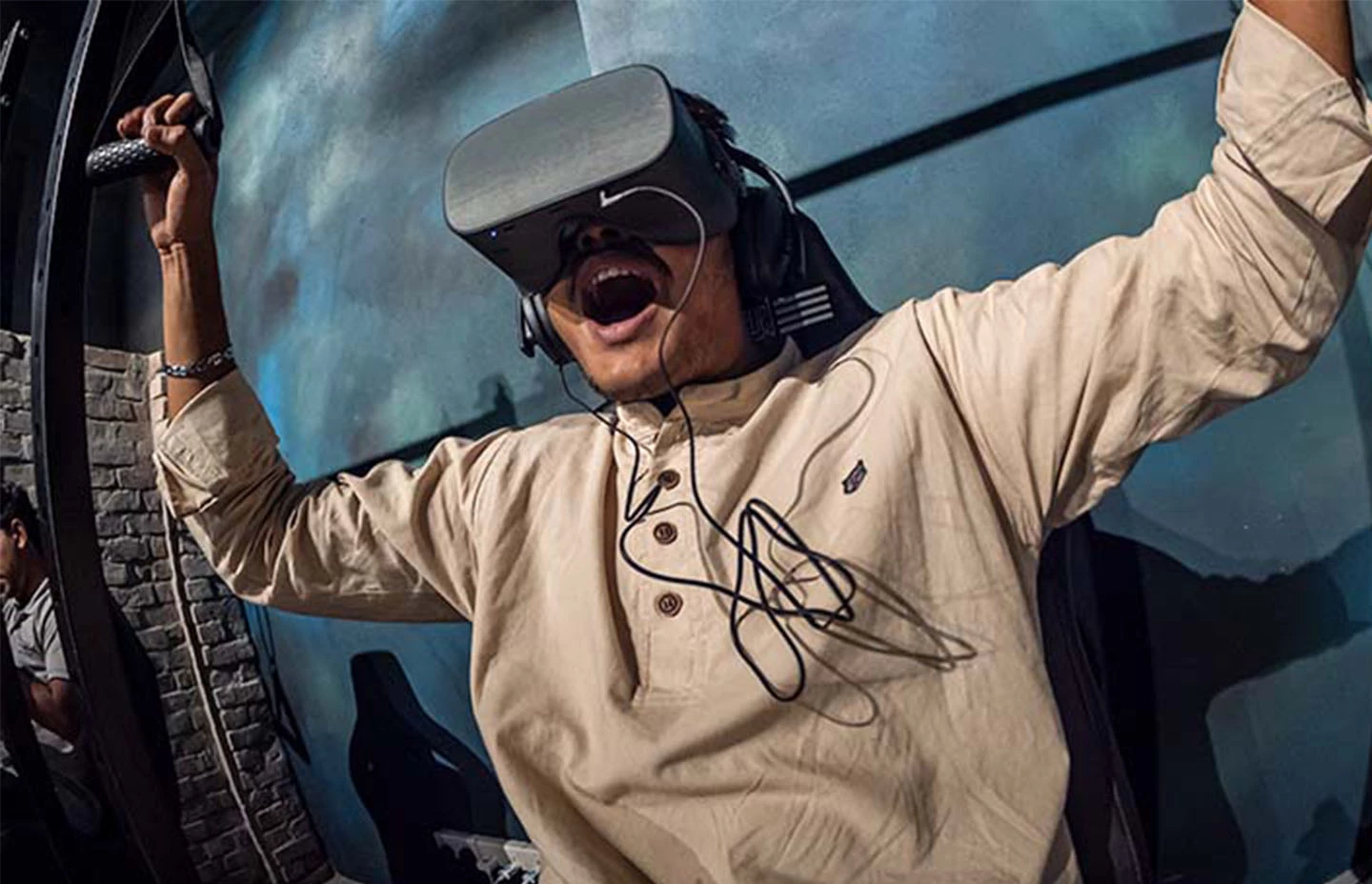 Man with open mouth sat on VR paraglider experience wearing a VR headset