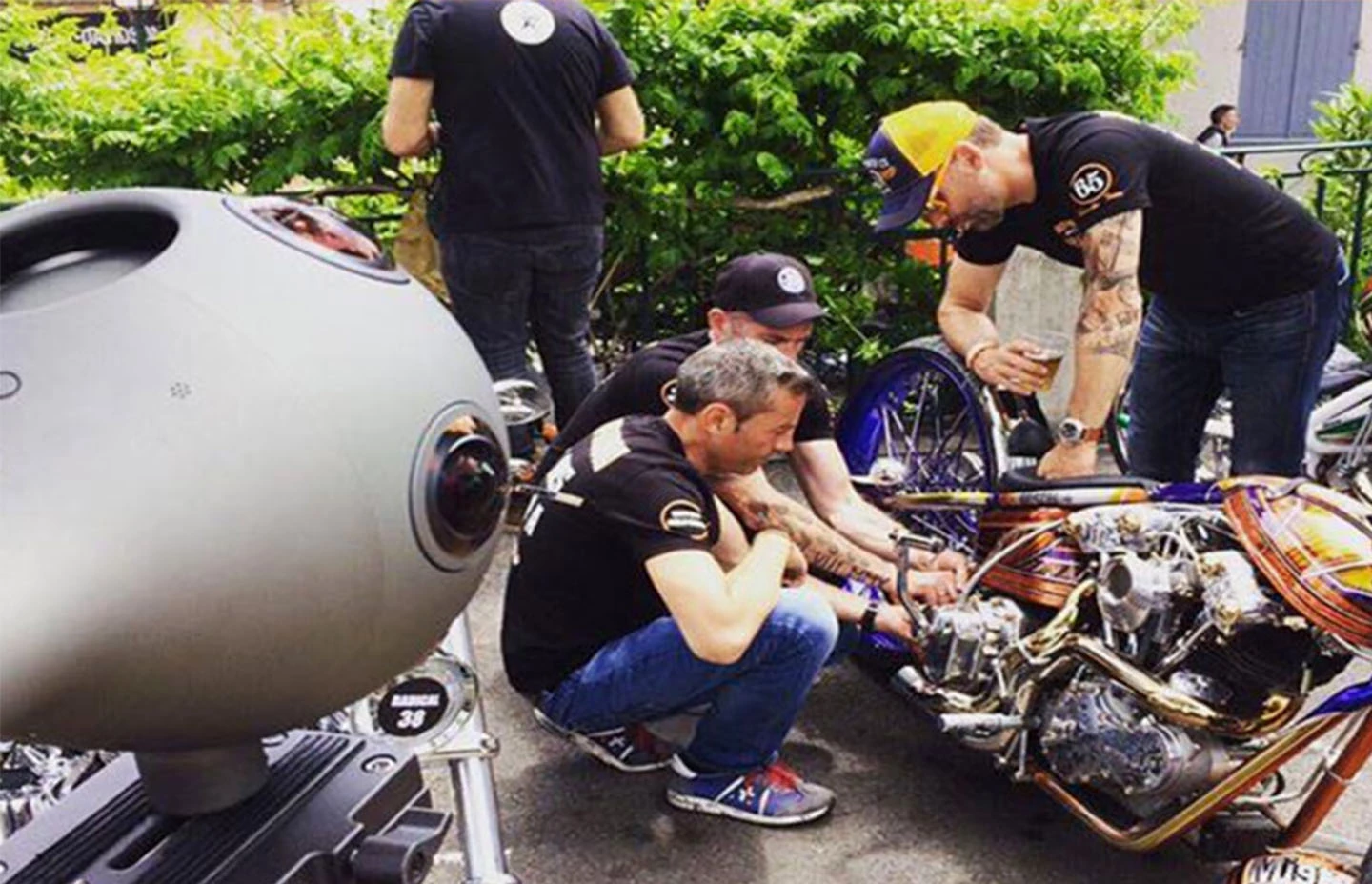 360 camera capturing footage of four men working on a Harley Davidson motorbike