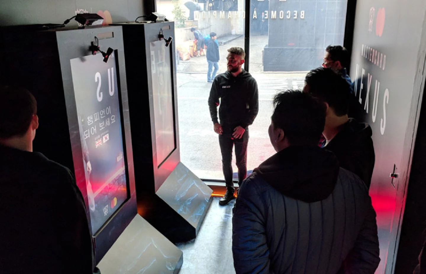 Five men standing around two Magic Mirror screens, watching the League of Legends Nexus experience
