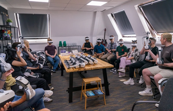 a room full of people surrounding a table wearing VR headsets