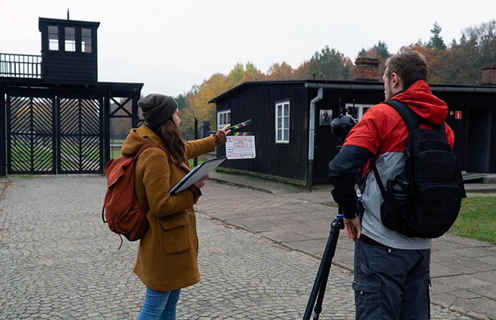 a woman holding a clapperboard next to a 360 degree camera with a filmmaker nearby