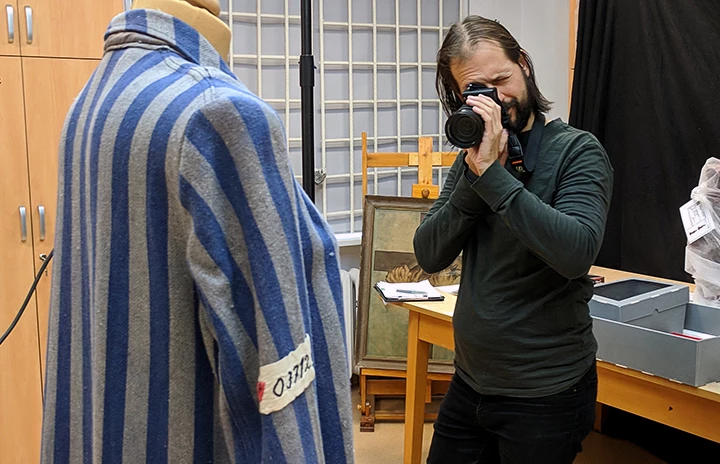 a man photographing historical clothing artifacts