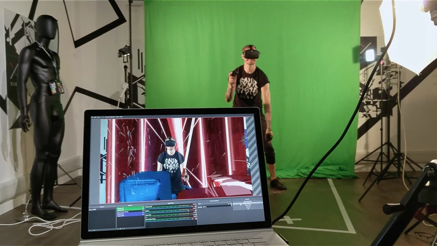 Man in Oculus virtual reality headset being filmed in front of green screen