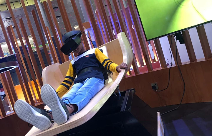 a man at an event sat on a moving segment of a waterslide wearing a VR headset